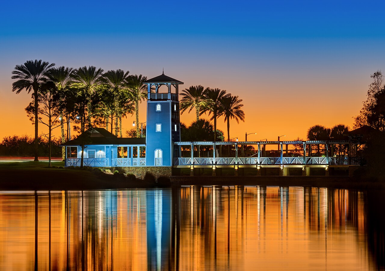 Lake Tradition lighthouse and boardwalk at twilight with palm trees reflected in the water